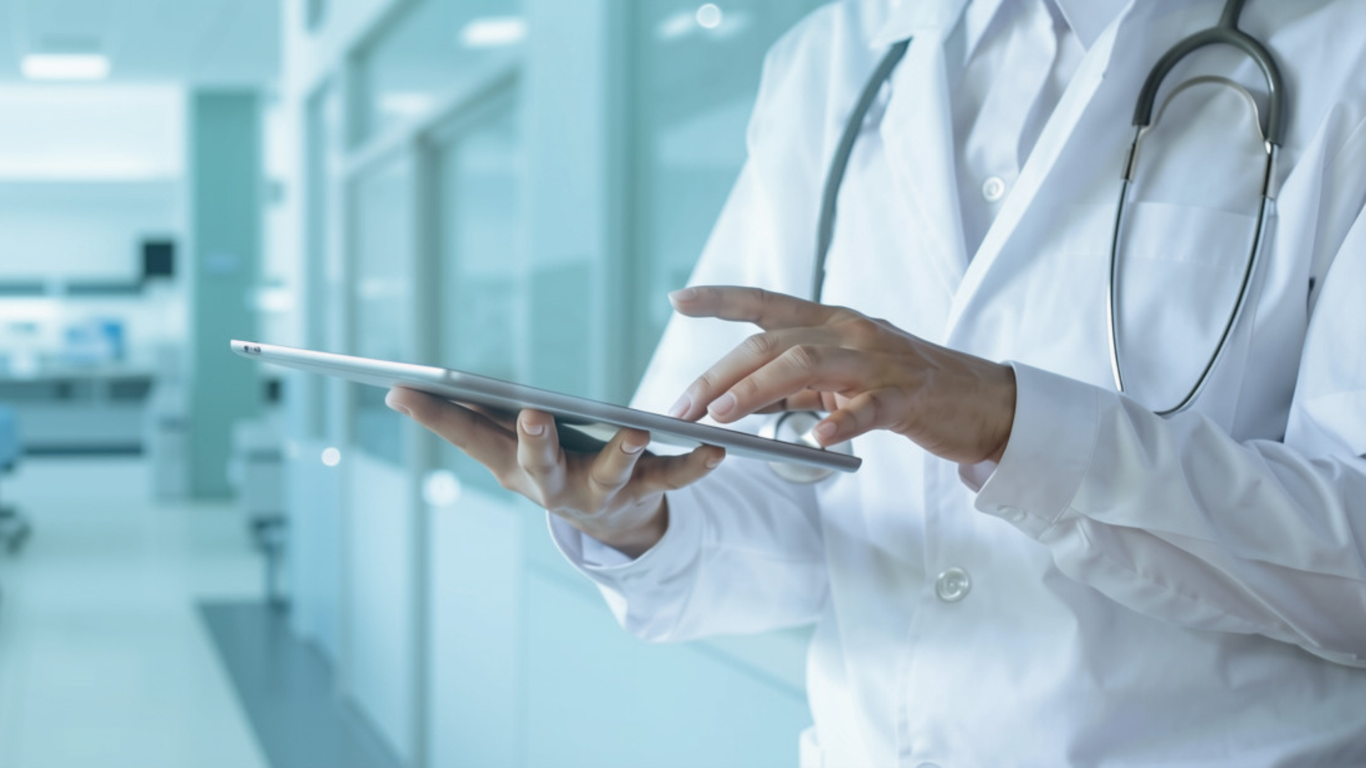 Healthcare professional using a tablet computer in a clinical setting, illustrating digital healthcare management and access to patient information.