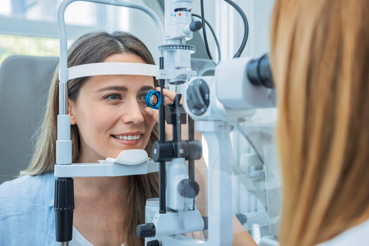 Lady in eye clinic getting her eye examined through a slit lamp