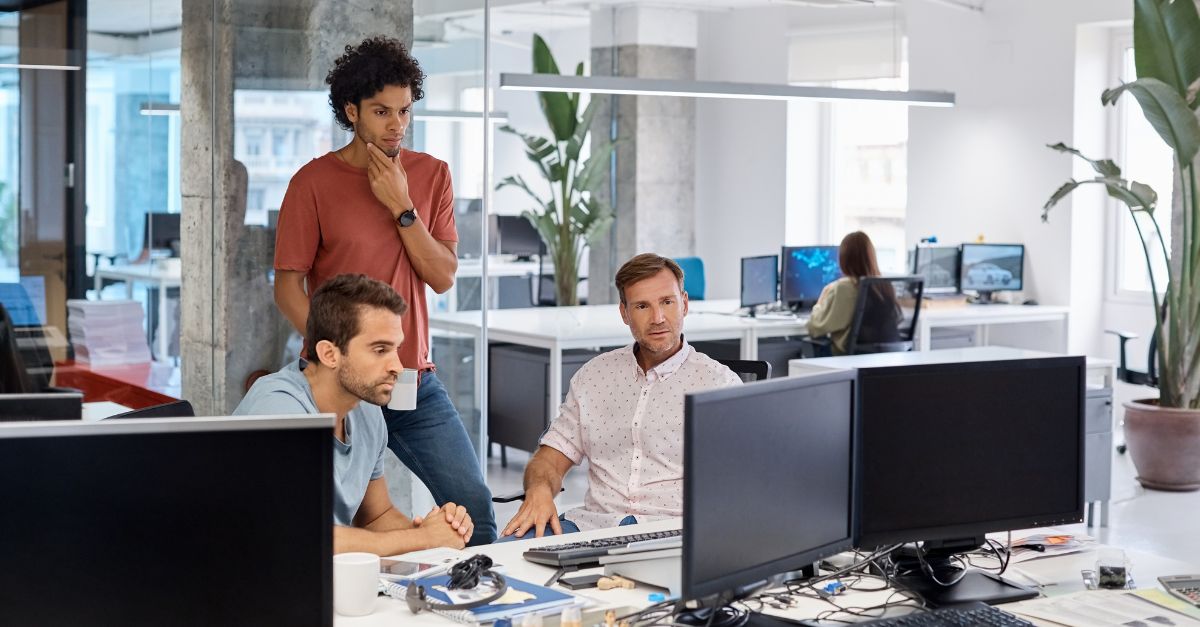 three men working around a computer together at their desks using NEC Housing