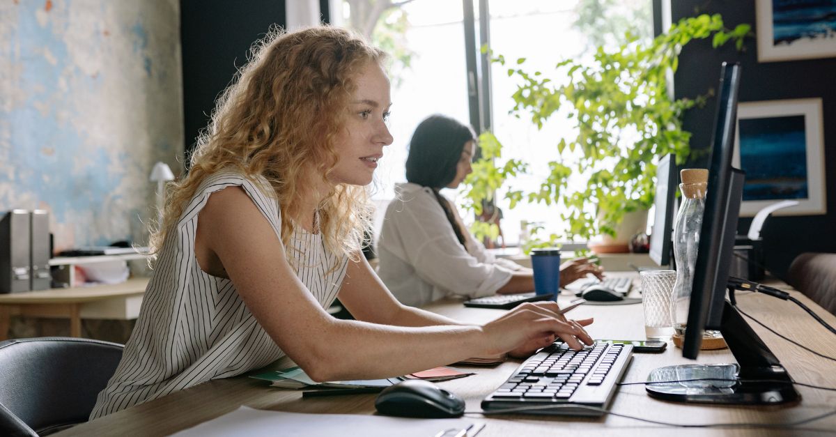 women working by a sunny window in an office using housing management software
