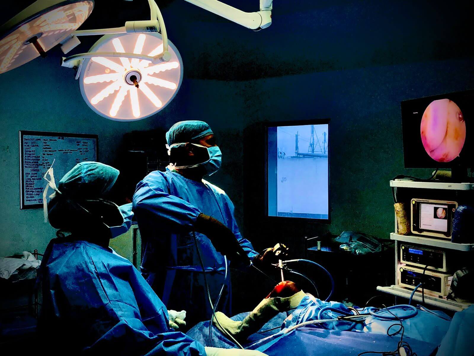 Healthcare professionals performing a procedure in an operating theatre.