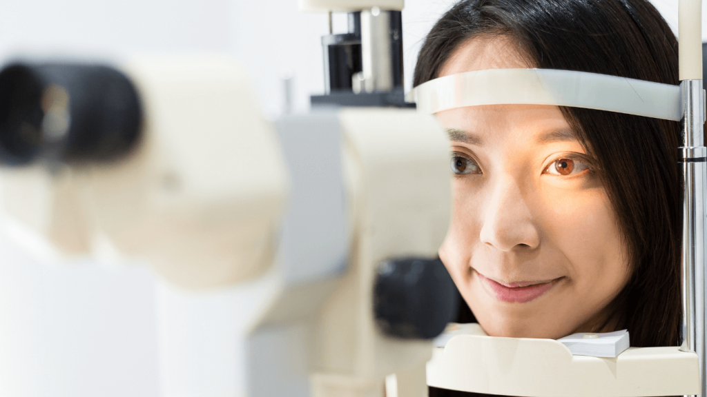 Person undergoing an eye examination with a slit lamp microscope, looking forward during a routine vision screening.