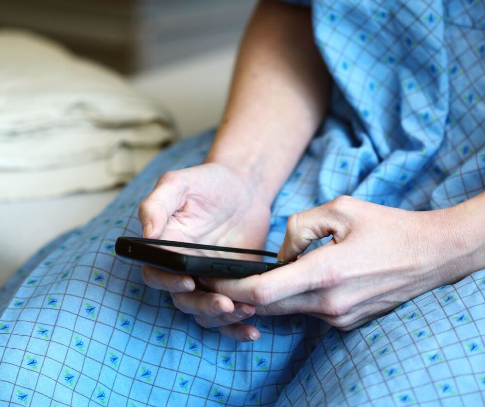 A patient holding and viewing a mobile phone.