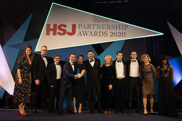 NEC, NHS Blood and Transplant, NHS Digital and Kainos receive the HSJ Partnership Awards 2020 on stage together.